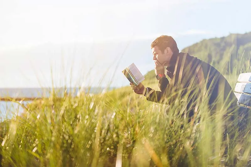 man sitting on bench reading a book