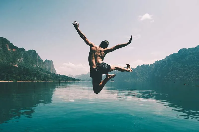 a guy jumping in a lake
