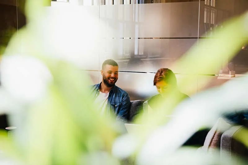 Two customer success managers sitting on a couch working on a customer journey project