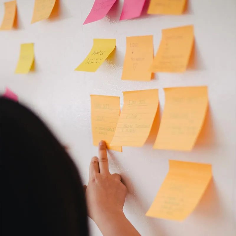 person pointing at sticky notes on a board