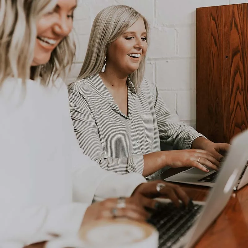 two women working on laptops