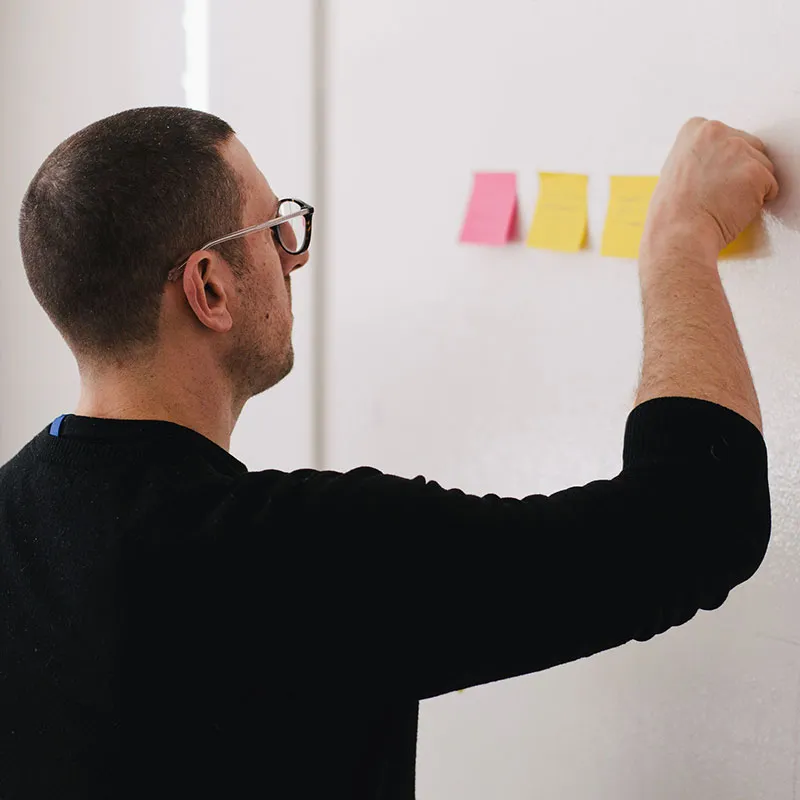 man posting sticky notes on a wall for a change management processes meeting