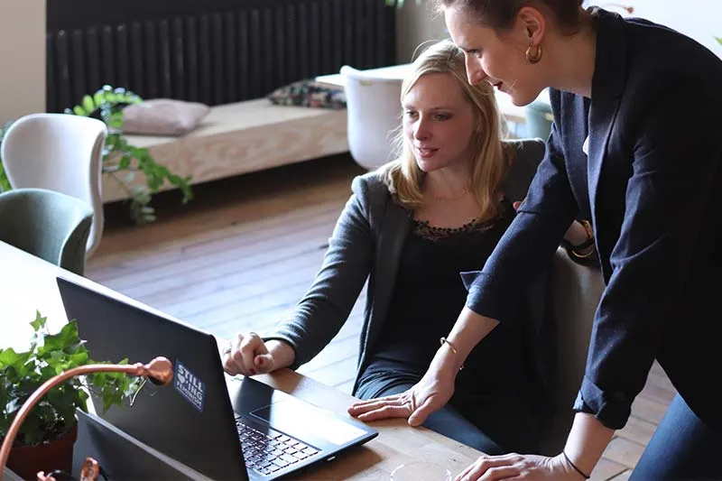 one employee showing another employee something on a laptop