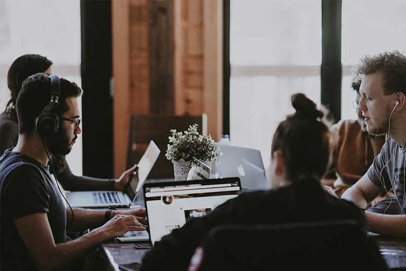 people sitting at a table working on their laptops