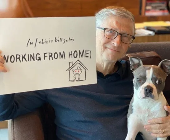 bill gates with his dog holding up a sign saying this is bill gates working from home