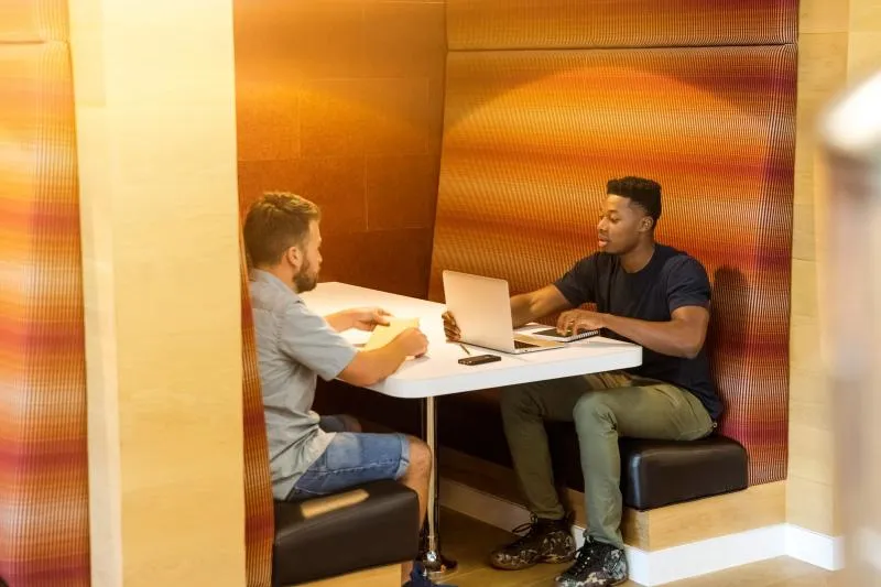 Two millenials working in a booth