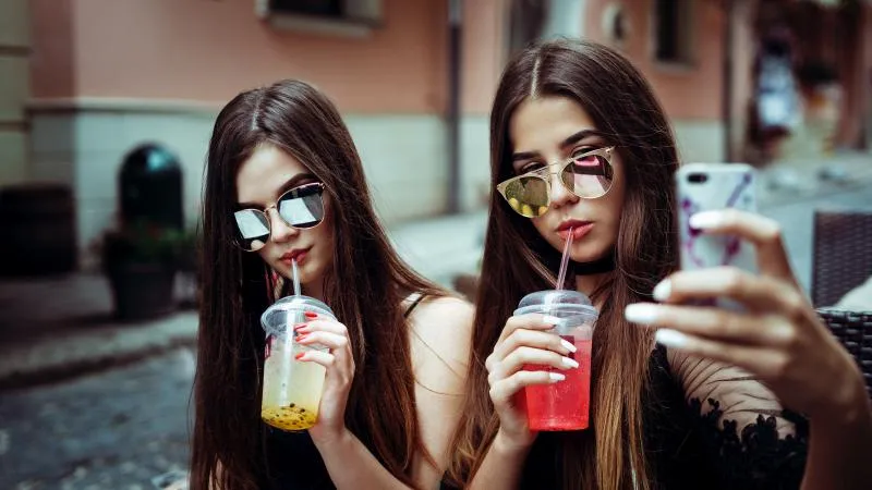 two millennial girls drinking cold beverages