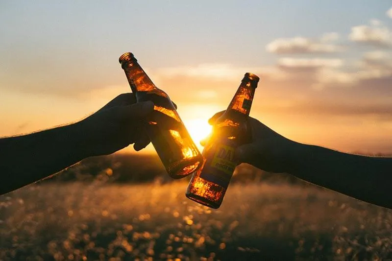 two friends celebrating with drinks in outdoors