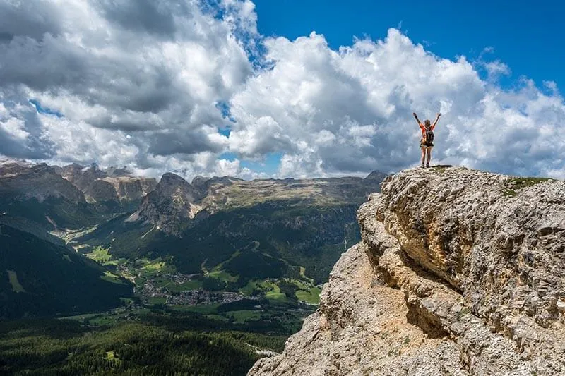 a guy on a cliff celebrating his accomplishment