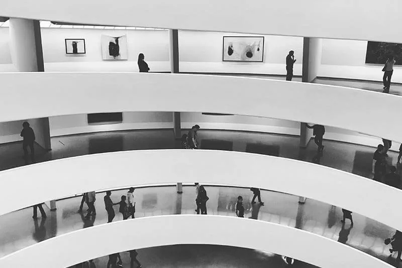 people walking in a white multi-story building at a art gallery