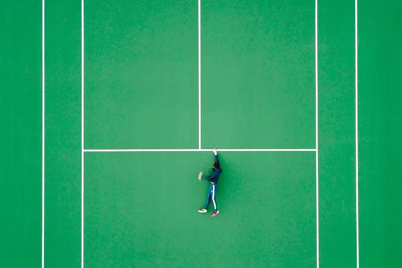 optical illusion of a guy hanging on the markings of a tennis court