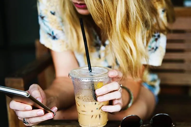 a girl on her cell phone drinks coffee