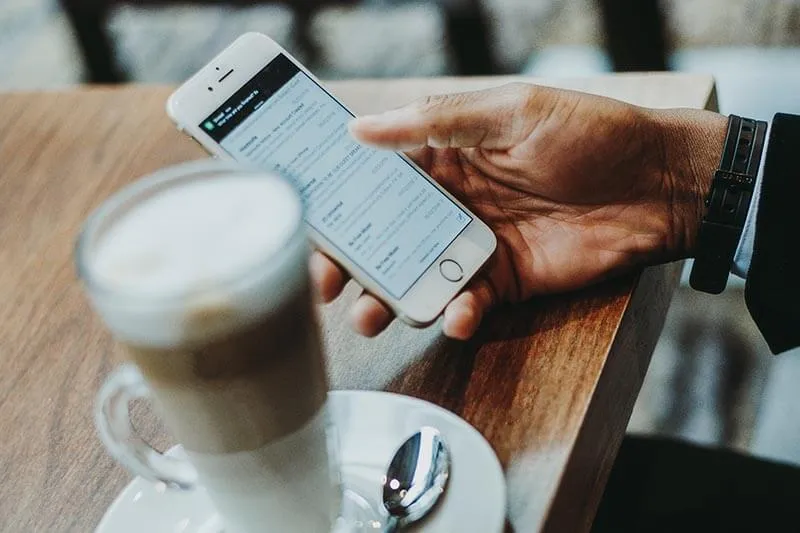 a man writing an email and sipping coffee