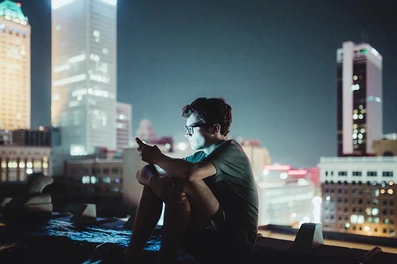 a guy on a terrace at night with his cell phone