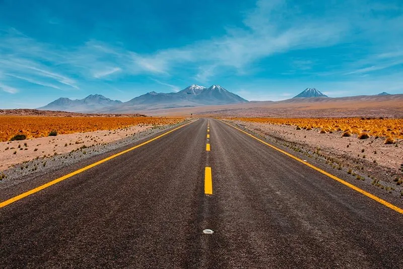 a straight highway leading to a mountain range