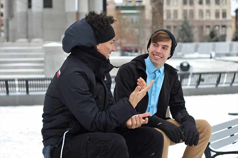two people sitting on a bench on a snowy day