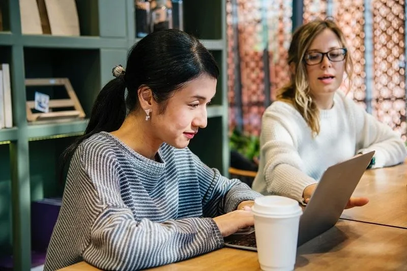 Two women working on their laptops at a coffee shop