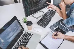 people working on laptop and writing in notebook