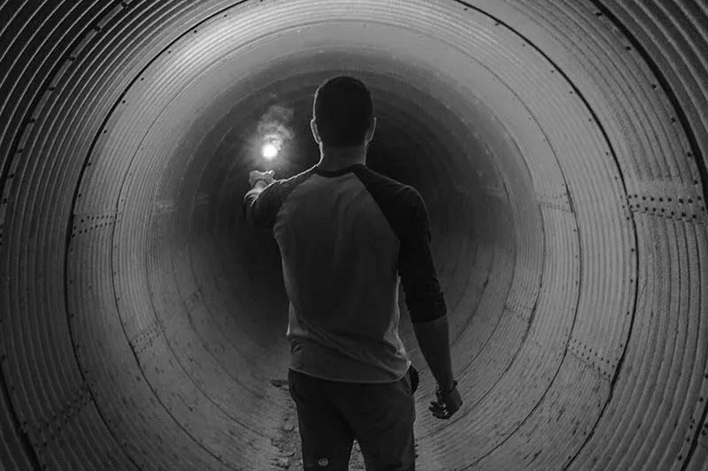 a person walking down a tunnel and seeing the light at the end