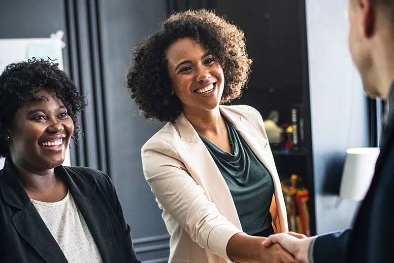 three people smiling and shaking hands in a business meeting