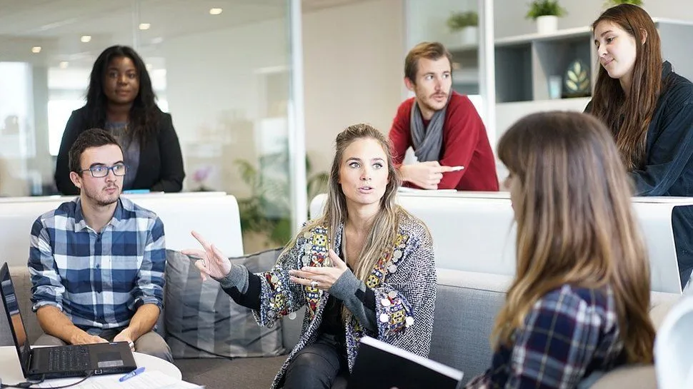 men and women having a discussion at a table in the workplace